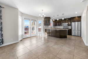 Kitchen with dark brown cabinetry, sink, hanging light fixtures, a kitchen island, and appliances with stainless steel finishes