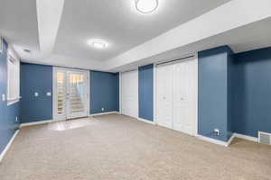 Basement with a textured ceiling and light colored carpet