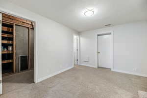 Carpeted empty room featuring a textured ceiling