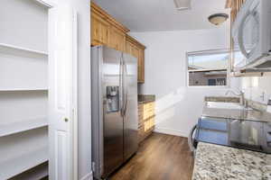 Kitchen with stone counters, sink, dark hardwood / wood-style floors, stainless steel fridge, and range