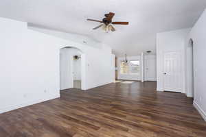 Unfurnished living room featuring ceiling fan, dark hardwood / wood-style flooring, and lofted ceiling