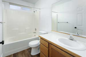 Full bathroom with hardwood / wood-style flooring, vanity, toilet, and shower / tub combination