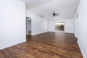 Empty room with ceiling fan, dark hardwood / wood-style flooring, and vaulted ceiling