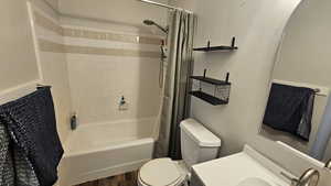 Full bathroom with hardwood / wood-style floors, vanity, shower / tub combo, and toilet