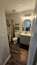 Full bathroom featuring vanity, hardwood / wood-style flooring, toilet, shower / bathtub combination with curtain, and a textured ceiling