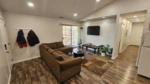 Living room with vaulted ceiling and dark wood-type flooring