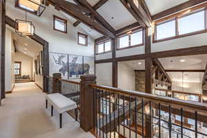 Hall featuring light carpet, beamed ceiling, and a towering ceiling