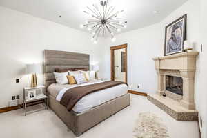 Bedroom with a high end fireplace and an inviting chandelier