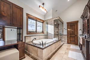 Bathroom with tile patterned floors, vanity, independent shower and bath, and lofted ceiling