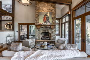 Living room featuring high vaulted ceiling, french doors, a stone fireplace, beamed ceiling, and wood-type flooring