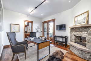 Office area with a stone fireplace, track lighting, and hardwood / wood-style flooring