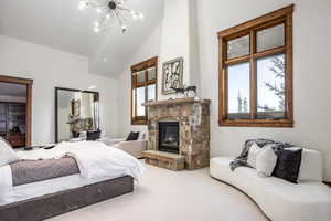 Bedroom with carpet, a notable chandelier, a fireplace, and vaulted ceiling