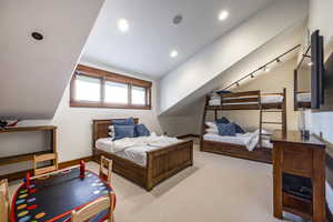 Bedroom with light colored carpet and lofted ceiling