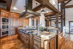 Kitchen with a center island, stainless steel appliances, light stone counters, pendant lighting, and island range hood