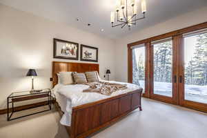 Carpeted bedroom with french doors, access to outside, and a notable chandelier