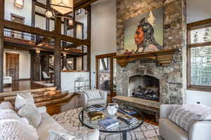 Living room featuring a stone fireplace, wood-type flooring, and a high ceiling