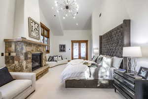 Bedroom featuring a notable chandelier, french doors, a fireplace, and vaulted ceiling