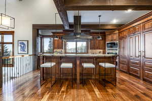 Kitchen featuring a kitchen breakfast bar, light stone countertops, stainless steel microwave, and hanging light fixtures