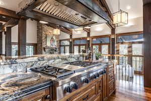 Kitchen with hardwood / wood-style floors, plenty of natural light, stainless steel gas stovetop, and custom exhaust hood