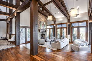 Unfurnished living room featuring french doors, a fireplace, high vaulted ceiling, beamed ceiling, and hardwood / wood-style floors