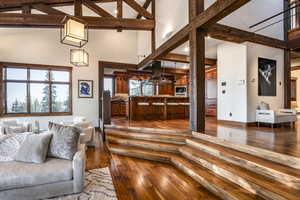 Living room with hardwood / wood-style flooring, high vaulted ceiling, and a healthy amount of sunlight