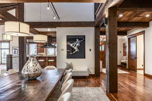 Dining area with beam ceiling, dark hardwood / wood-style floors, and track lighting