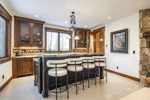 Kitchen featuring a kitchen bar, decorative backsplash, a kitchen island, and decorative light fixtures