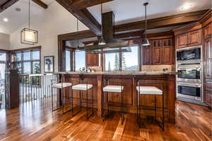 Kitchen featuring beam ceiling, black microwave, dark hardwood / wood-style flooring, backsplash, and decorative light fixtures