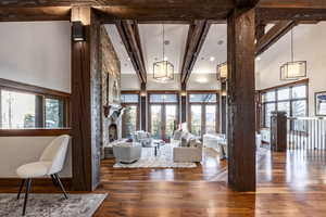 Living room with beam ceiling, a stone fireplace, dark wood-type flooring, and high vaulted ceiling