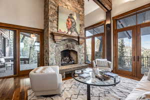 Living room featuring a stone fireplace, french doors, and wood-type flooring