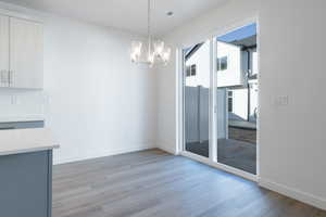 Unfurnished dining area with light hardwood / wood-style floors and a notable chandelier