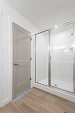 Bathroom with hardwood / wood-style flooring and a shower with shower door