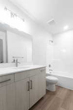 Full bathroom featuring bathing tub / shower combination, vanity, wood-type flooring, and toilet