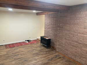 Basement featuring dark hardwood / wood-style flooring, a wood stove, and brick wall