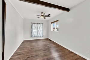 Empty room featuring beamed ceiling, ceiling fan, and dark wood-type flooring