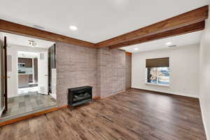 Unfurnished living room featuring beam ceiling and hardwood / wood-style floors