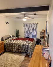 Bedroom with beamed ceiling, ceiling fan, ornamental molding, and hardwood / wood-style floors