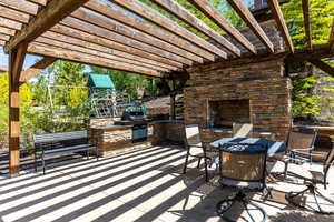 View of patio / terrace with a pergola, area for grilling, a playground, and an outdoor stone fireplace