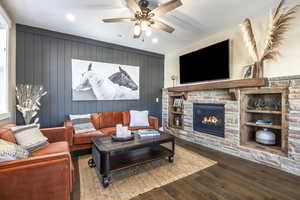 Living room featuring hardwood / wood-style flooring, ceiling fan, and wood walls