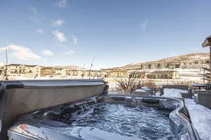 Snow covered pool featuring a hot tub