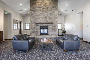 Carpeted living room with a fireplace, high vaulted ceiling, and plenty of natural light