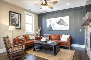 Living room with wood walls, ceiling fan, and wood-type flooring