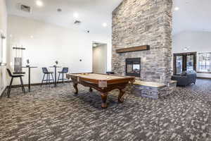 Recreation room with a fireplace, dark colored carpet, lofted ceiling, and pool table