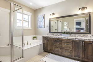 Bathroom featuring plus walk in shower, vanity, and tile patterned floors