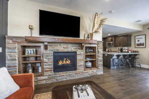 Living room with a fireplace, sink, and dark wood-type flooring