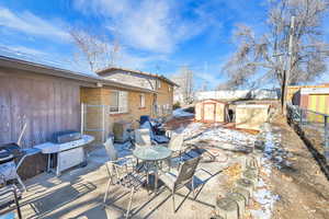 Snow covered patio with a storage unit and area for grilling