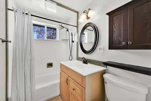 Full bathroom with vanity, toilet, and shower / bath combo with shower curtain