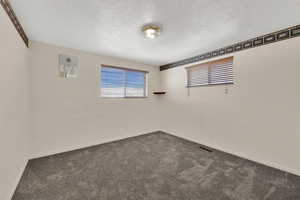 Carpeted empty room featuring a textured ceiling