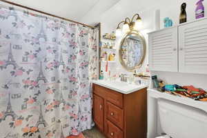 Bathroom featuring a shower with curtain, vanity, and toilet