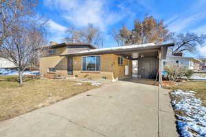 Split level home featuring a lawn and a carport